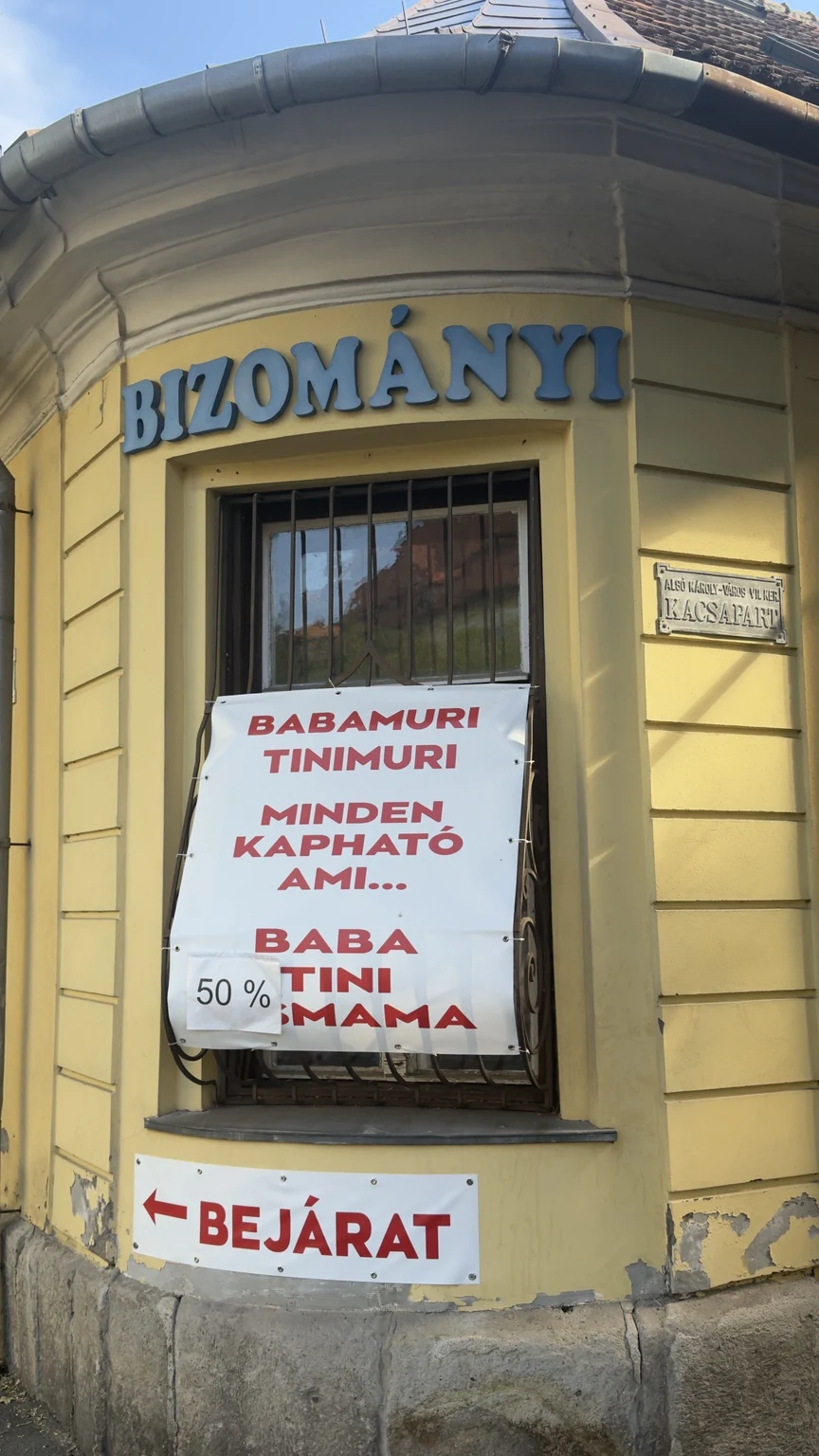 Bizományi üzlet ablaka lelógó Babamuri Tinimuri molinóval és ráragasztott 50 százalékos lappal