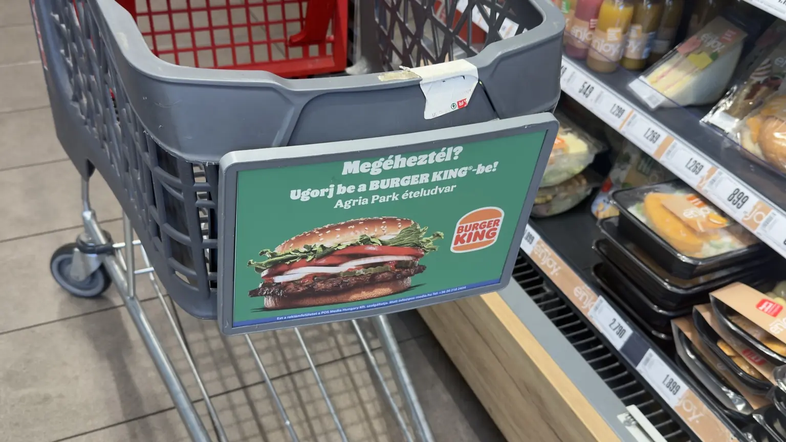 Burger King-hirdetés egy bevásárlókocsira szerelt reklámtáblán, élelmiszerüzleti környezetben