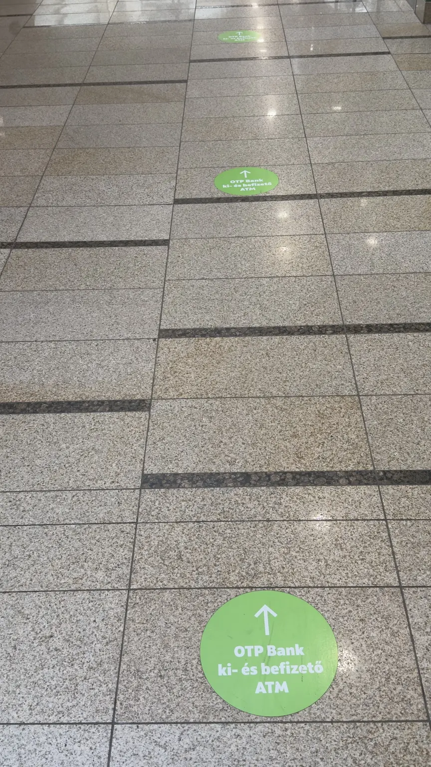 Közelebbi nézet az OTP Bank ki- és befizető ATM felé mutató padlómatrica-soráról