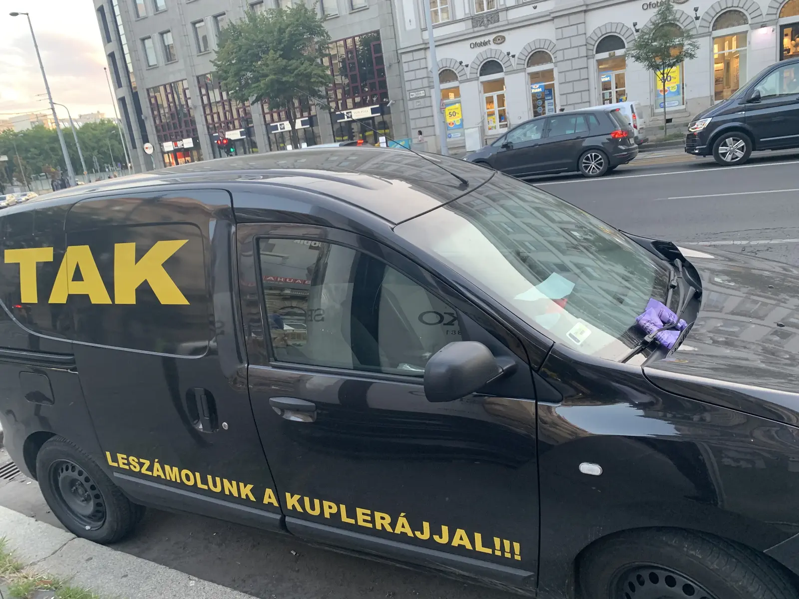 Fekete TAK kisáruszállító nagy sárga márkanévvel és Leszámolunk a kuplerájjal felirattal Budapesten
