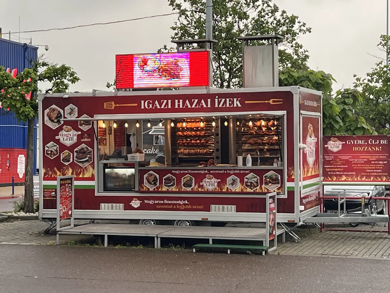 Teljes felületén bordó Magyar Grill márkajelzésekkel, ételfotókkal és feliratokkal borított mobil vendéglátóegység Egerben