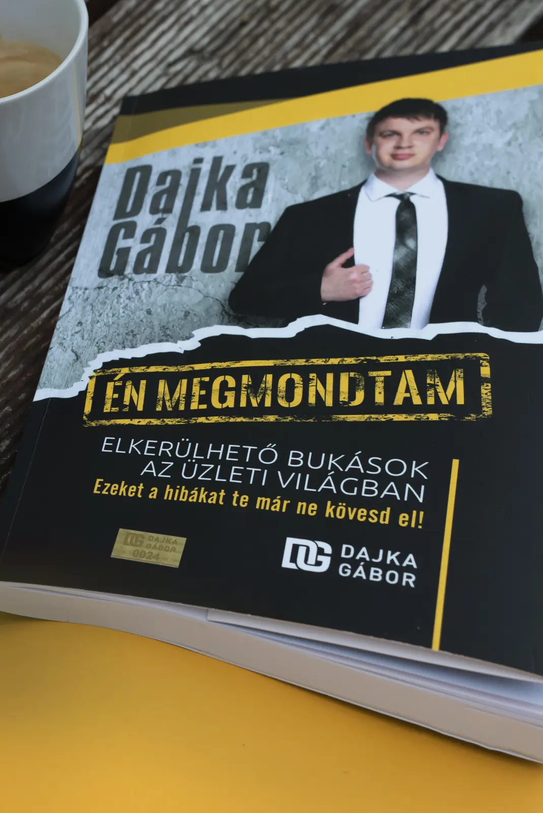 Dajka Gábor könyve kávéval sötét fa felületen